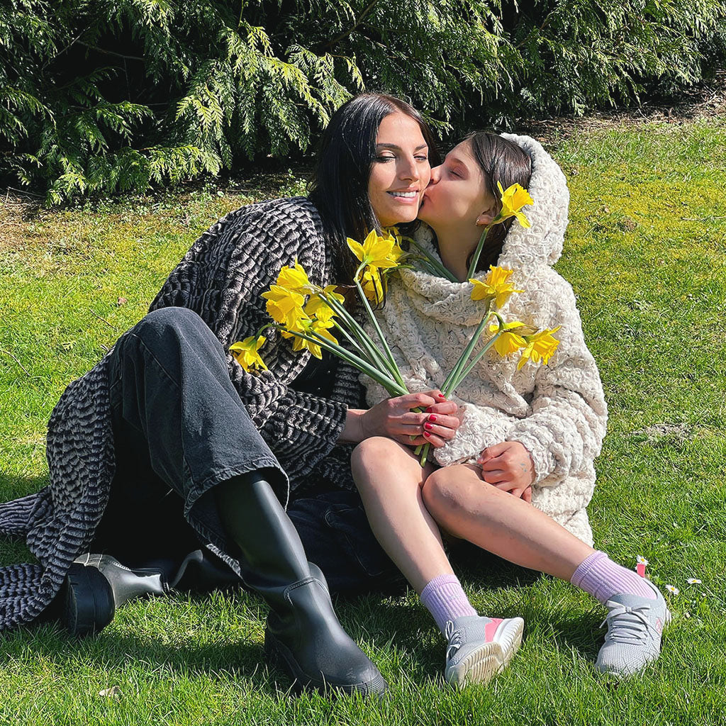 mother and child holding daffodils and wearing faux fur coverups handmade by Pandemonium Seattle USA