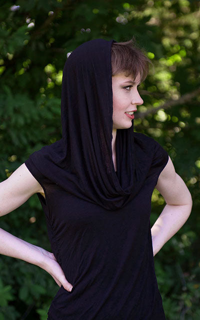 Model wearing the Hooded Cowl Top with hood up a This top can be worn as a cowl neck, off-shoulder, or hooded style. | Abyss a alight weight jersey knit in black | Handmade in Seattle WA | Pandemonium Millinery