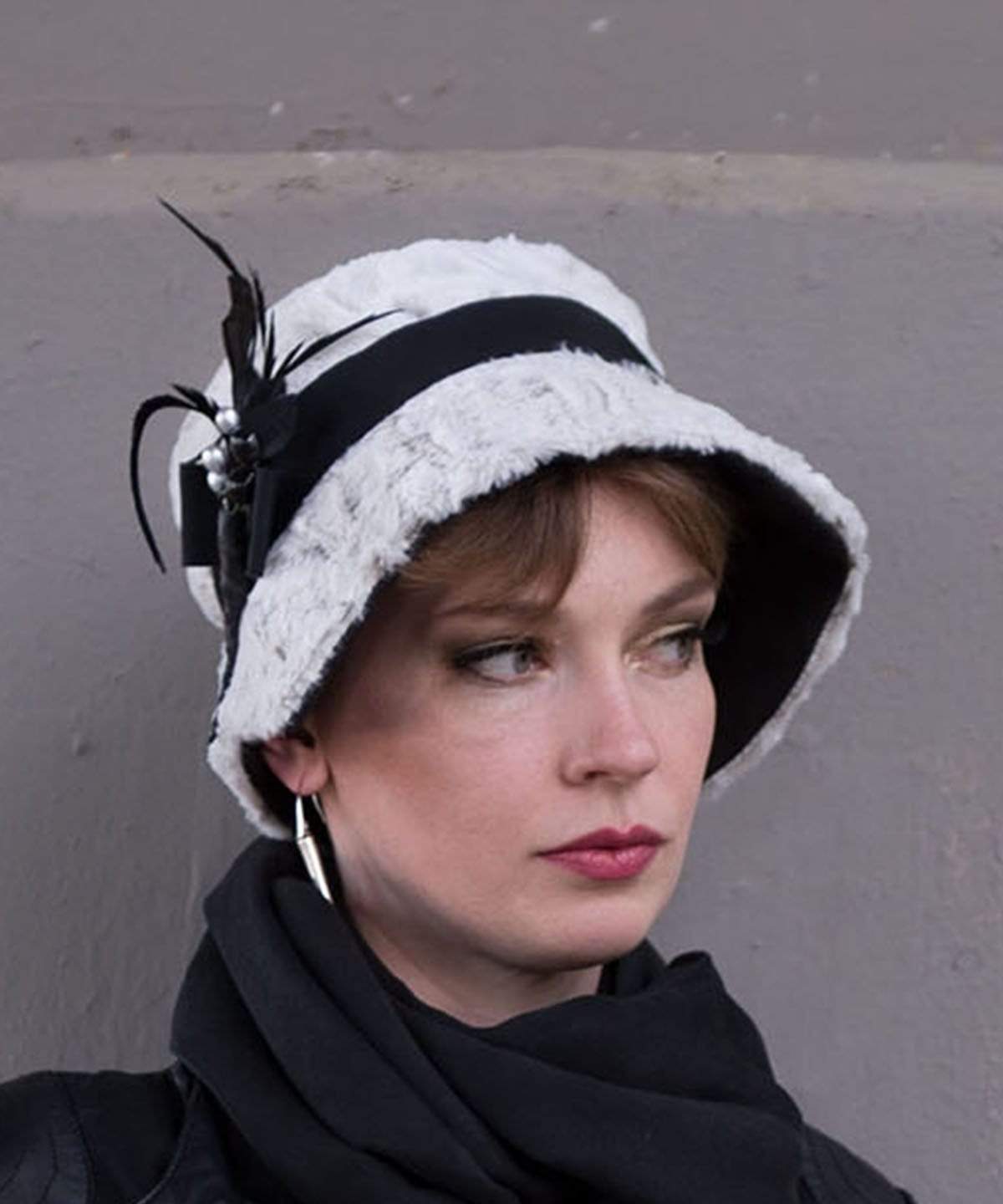 Woman wearing Abigail Hat in Winter’s Frost White Luxury Faux Fur with Black Faux Suede under rim. Trimmed with Black Grosgrain Band and Feathers| Handmade in Seattle WA| Pandemonium Millinery