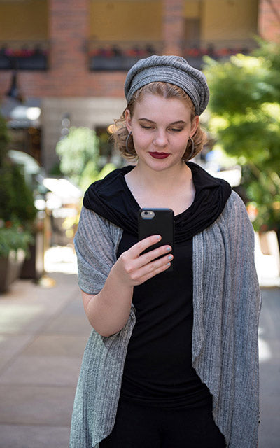Model  outdoors holding a cellphone wearing the Handkerchief Scarf and matching Rowdie in rain voile with a coordinating Hooded Cowl Top a This top can be worn as a cowl neck, off-shoulder, or hooded style. | Abyss a lightweight jersey knit in black | Handmade in Seattle WA | Pandemonium Millinery