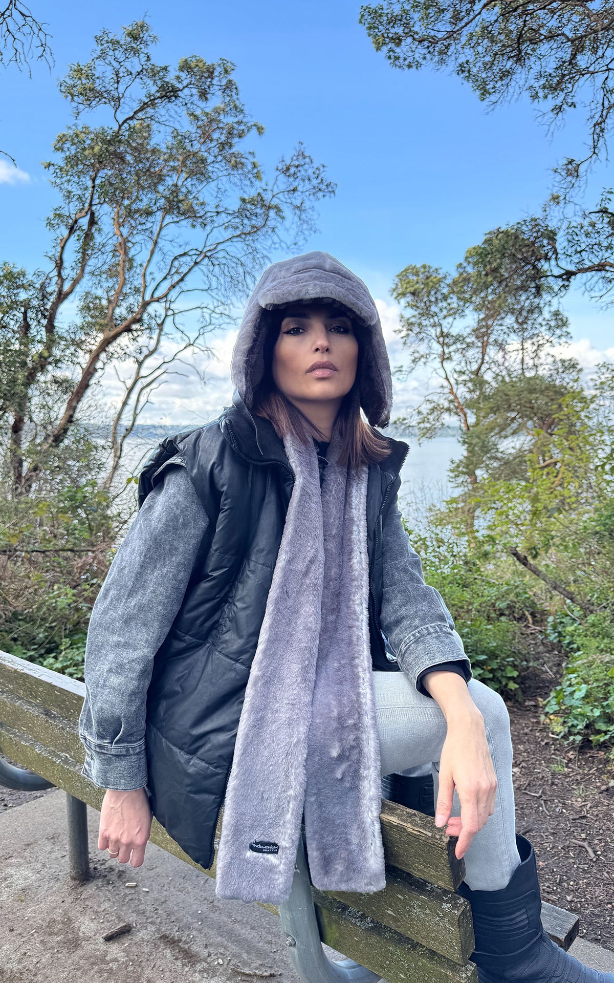 A woman sitting on a bench wearing a Skinny Scarf in Olympic Fog Plush Faux Fur with matching Aviator Hat. Handmade in Seattle, WA , USA by Pandemonium Millinery