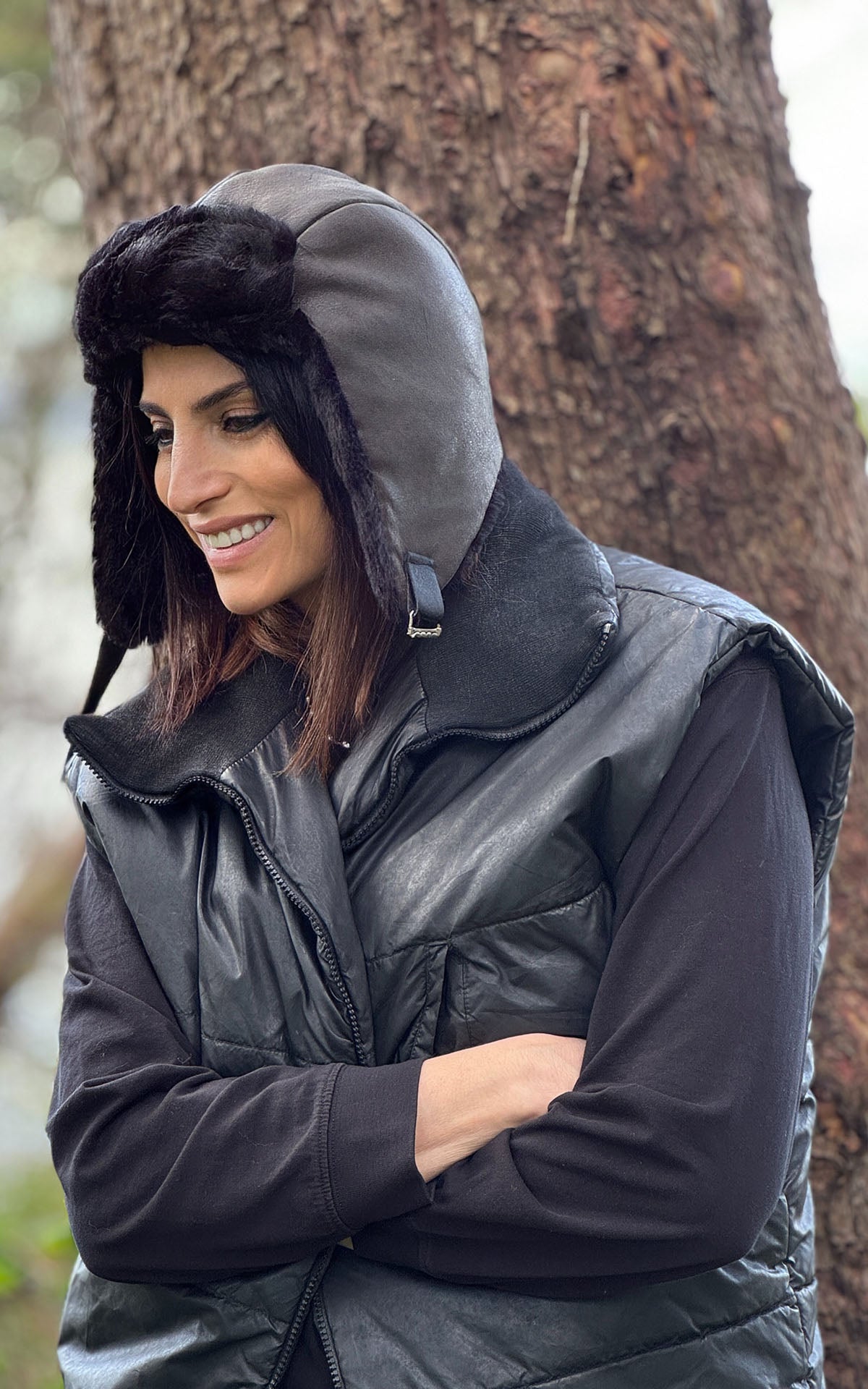 Side view of a woman folding her arms and wearing a Aviator Hat in Vegan Leather Rustic in Olive  with Cuddly Faux Fur in Black. Handsewn in Seattle, WA , USA by Pandemonium Millinery