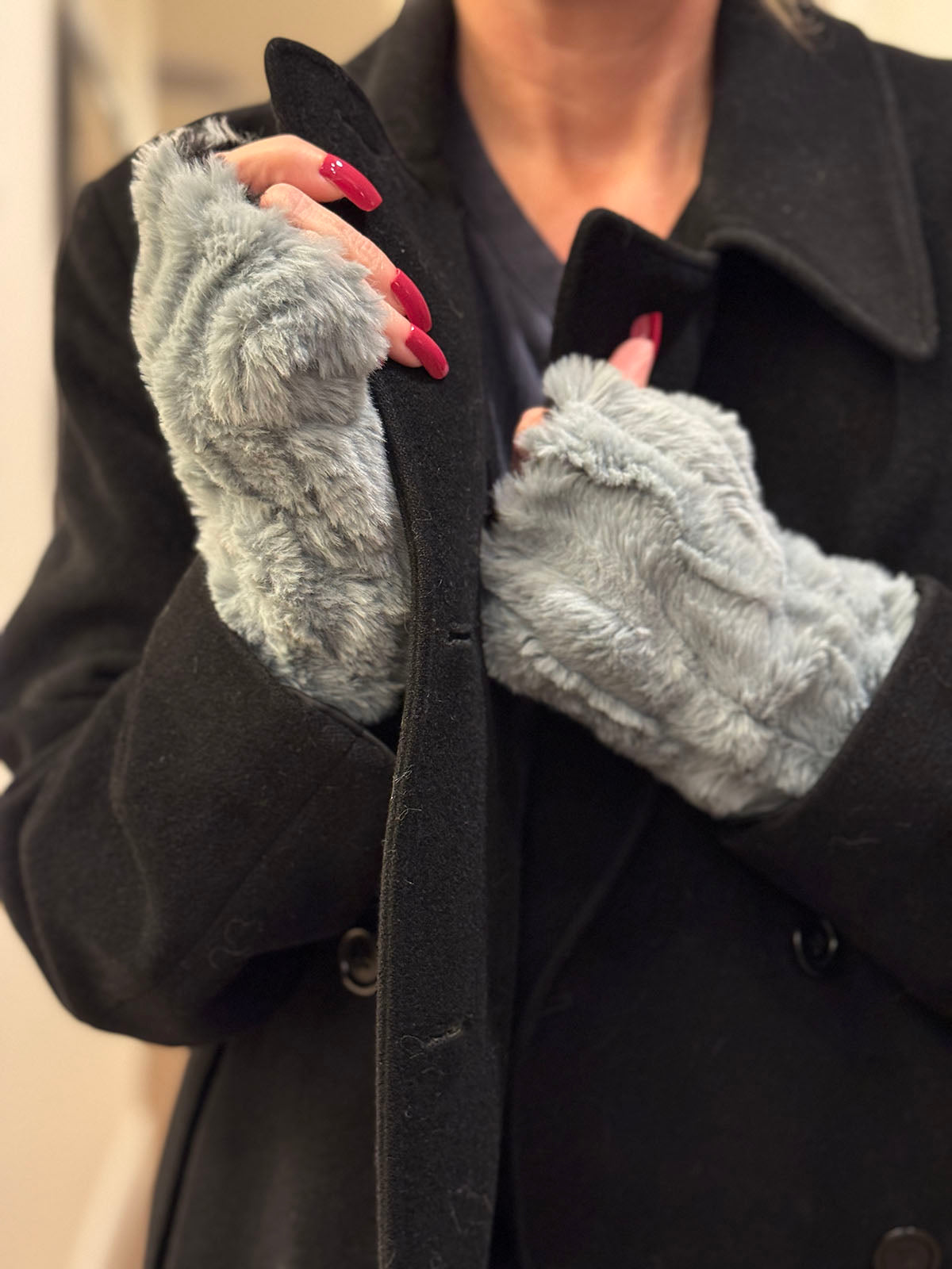 Woman wearing Cirrus Blue Mist Fingerless Gloves while buttoning her coat. Made in Seattle, WA, USA by Pandemonium Seattle.