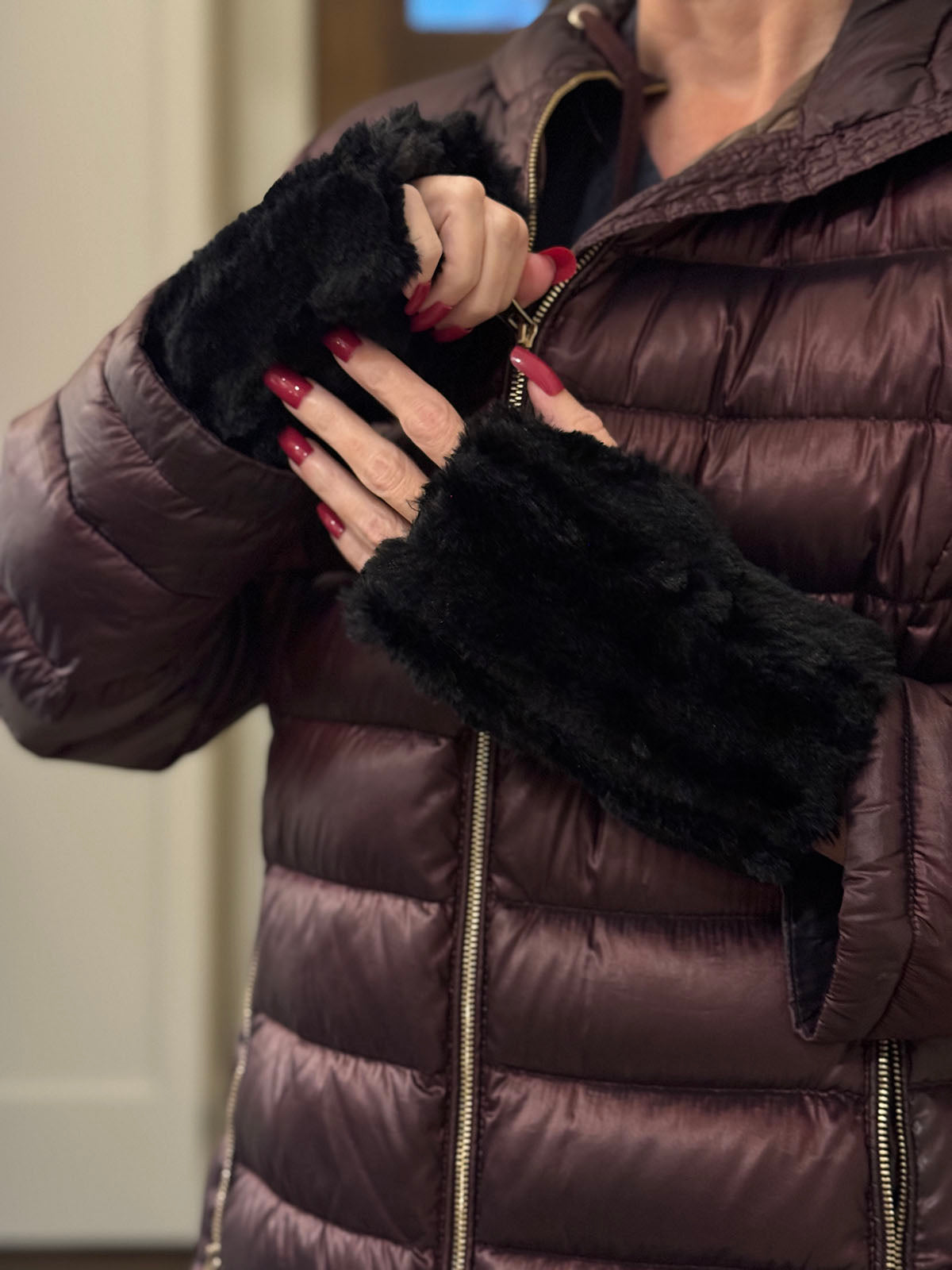 Woman zipping up her puffer coat while wearing black Cirrus in Shadow Fingerless Gloves. Made in Seattle, WA, USA by Pandemonium Seattle.
