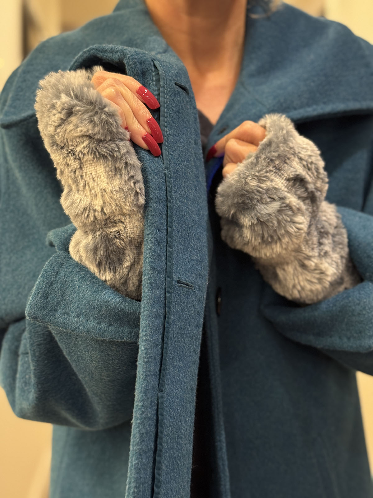 Woman wearing Cloudwalk Blue Mist Fingerless Gloves and buttoning a coat. Made in Seattle, WA, USA by Pandemonium Seattle.