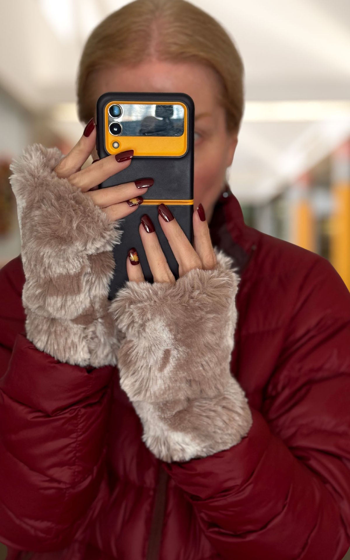 Woman wearing Cloudwalk Honey Fingerless Gloves and holding a cell phone. Made in Seattle, WA, USA by Pandemonium Seattle.