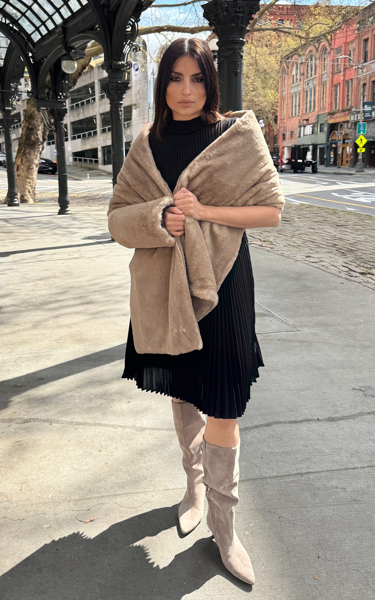 Woman standing on sidewalk in the city wearing the Stole in Golden Bluff Faux Fur over a Black dress.  Handmade by Pandemonium Seattle. Seattle, WA USA