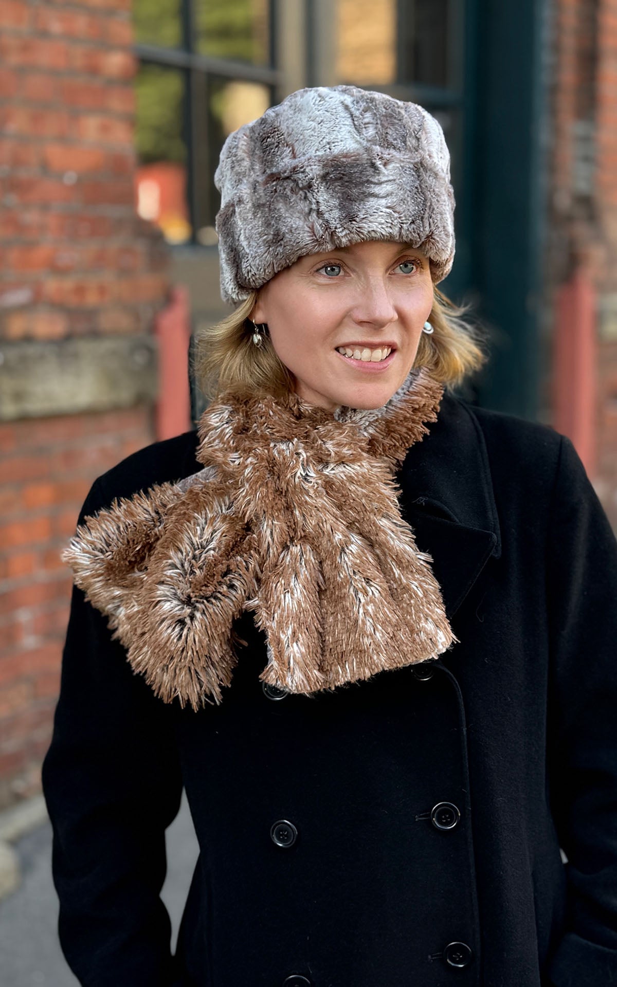 A woman wearing a Cuffed Pillbox in Rusty Rock Faux Fur with a matching Pull-Thru-Scarf shown reversed to the Red Fox side. Scarf is Rusty Rock and reversible to Red Fox Faux Fur. Made in Seattle, WA, USA by Pandemonium Seattle.