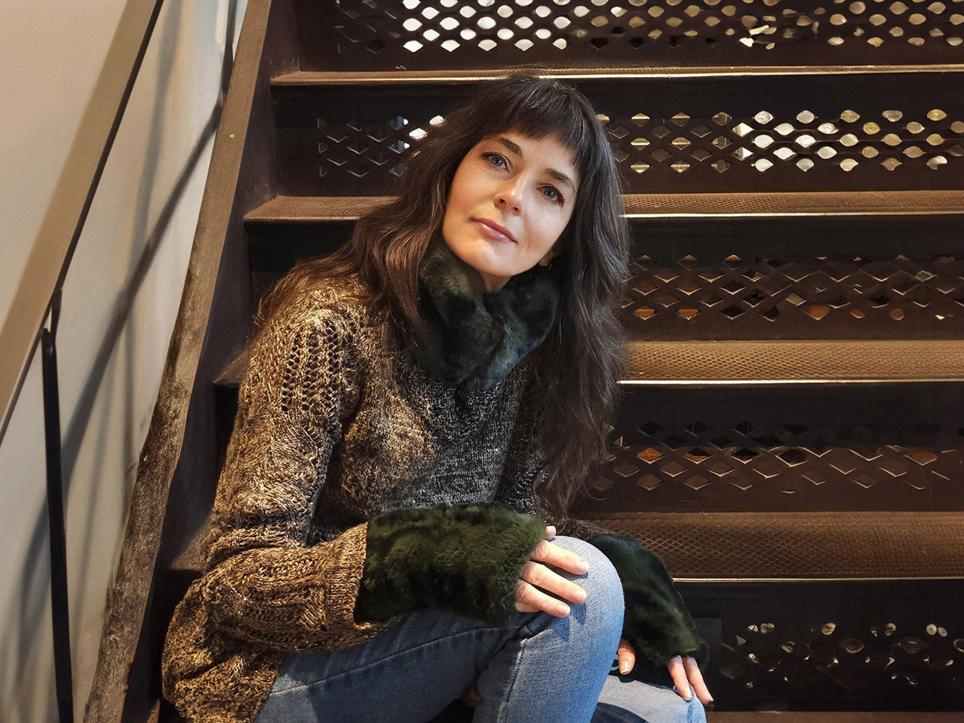 woman sitting on stairs wearing a dark green faux fur neck cozy and glove set handmade in America by Pandemonium Seattle