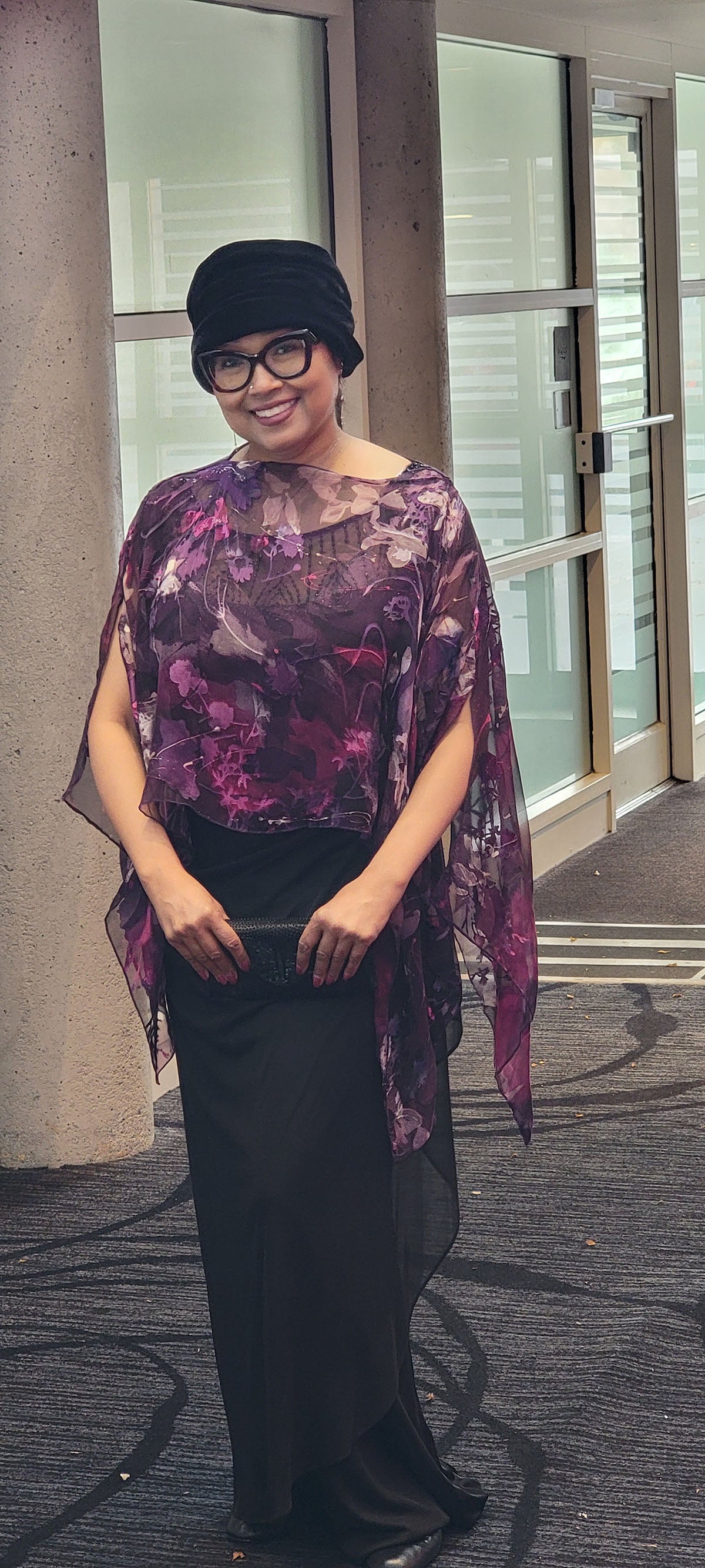 Woman wearing the Garden Path Silk Poncho in Azalea while walkingin a hotel. Made in Seattle, WA, USA by Pandemonium Millinery.