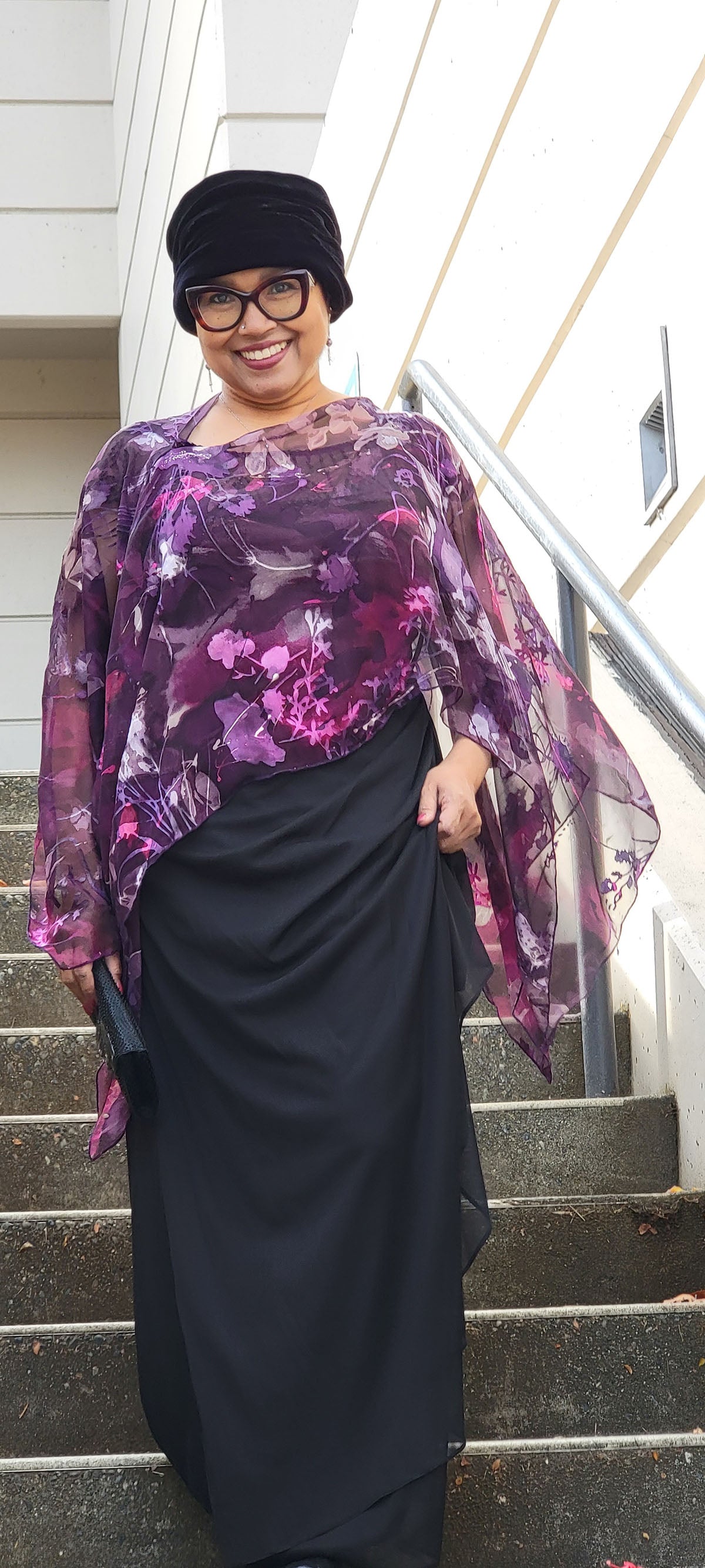 Woman wearing the Garden Path Silk Poncho in Azalea while walking down a staircase. Made in Seattle, WA, USA by Pandemonium Millinery.