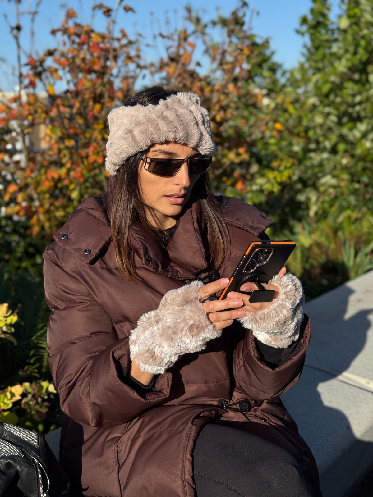 Woman wearing a Cirrus Honey Headband and Cloudwalk Honey Fingerless Gloves, while viewing her phone. Handmade in Seattle, WA, USA by Pandemonium Millinery.