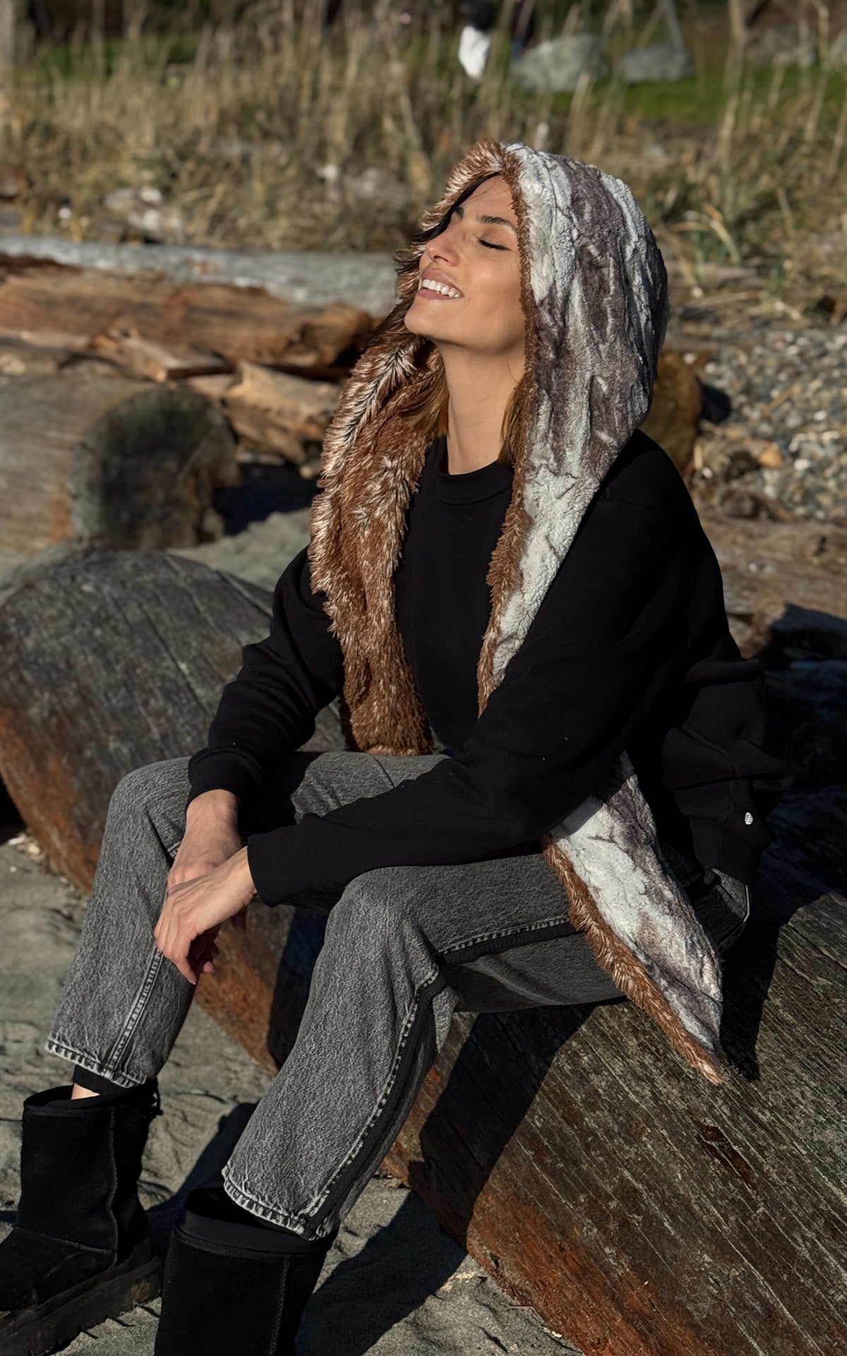 Woman wearing the Hoody Scarf in Rusty Rock and Red Fox, while sitting in the sun at the beach in Seattle. Made in Seattle, WA, USA by Pandemonium Seattle.