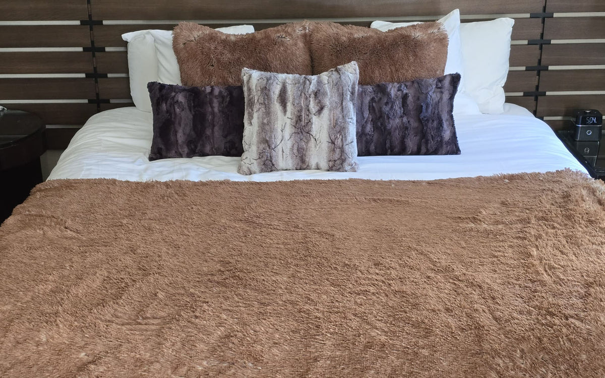 Plush and fluffy Red Fox Faux Fur Throw shown on a bed with crisp, white bedding. Also shown with matching and complementary faux fur throw pillows in Red Fox, Espresso Bean and Rusty Rock. Made in Seattle, WA, USA by Pandemonium Seattle.