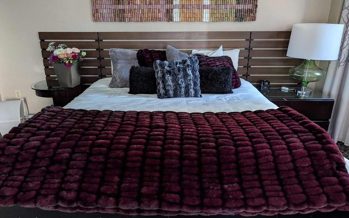 Bedroom with dramatic Cherry Bomb Royal Opulence Faux Fur Throw Blanket spread across the bed. Shown with matching and complementary Throw Pillows in Cherry Bomb, Black Swan, Cloudwalk Shadow and Olympic Fog faux furs. Made in Seattle, WA, USA by Pandemonium Seattle.