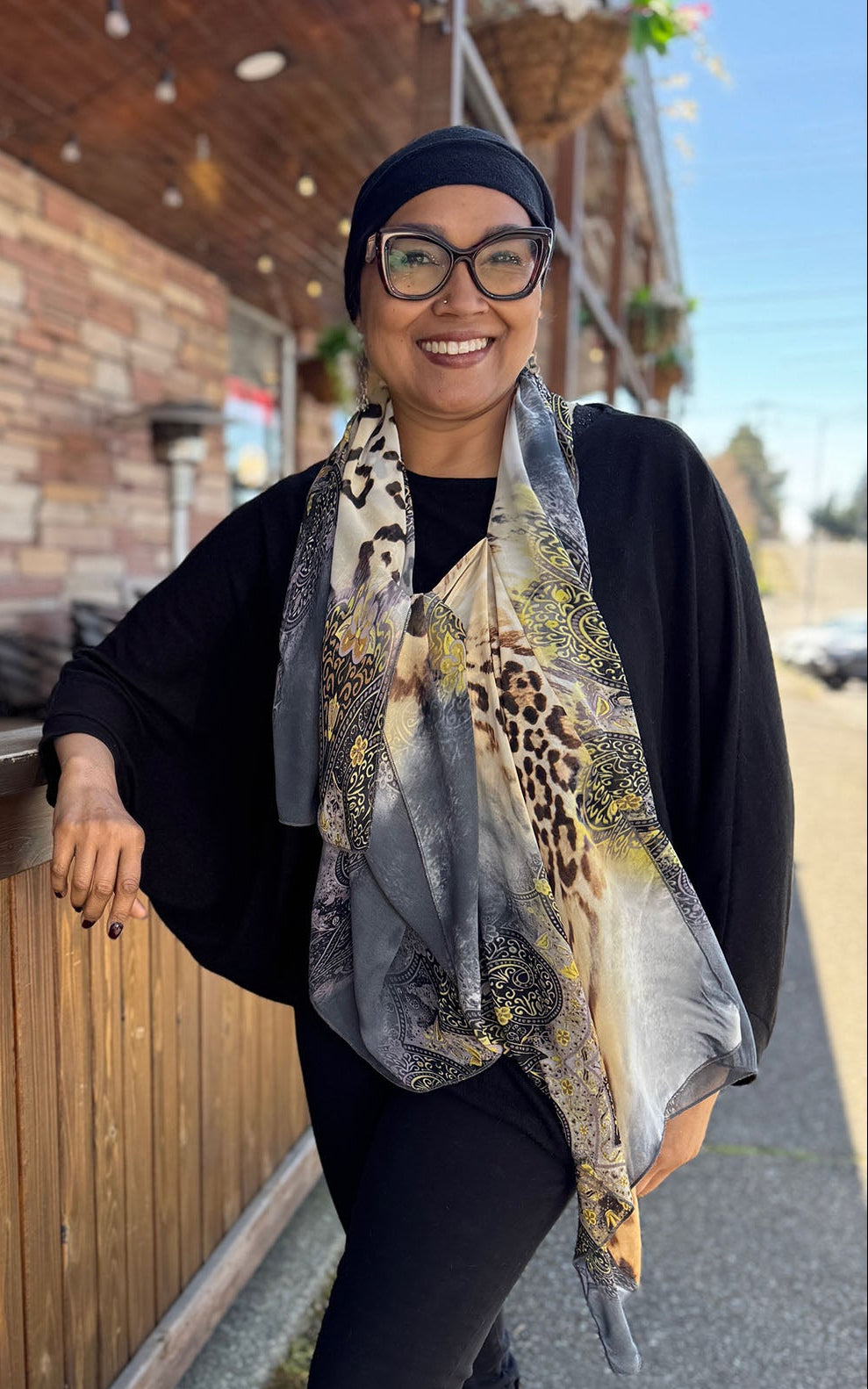 Woman wearing the Lumina Poncho in Party Animal, shown styled as a scarf. Made in Seattle, WA, USA by Pandemonium Seattle.