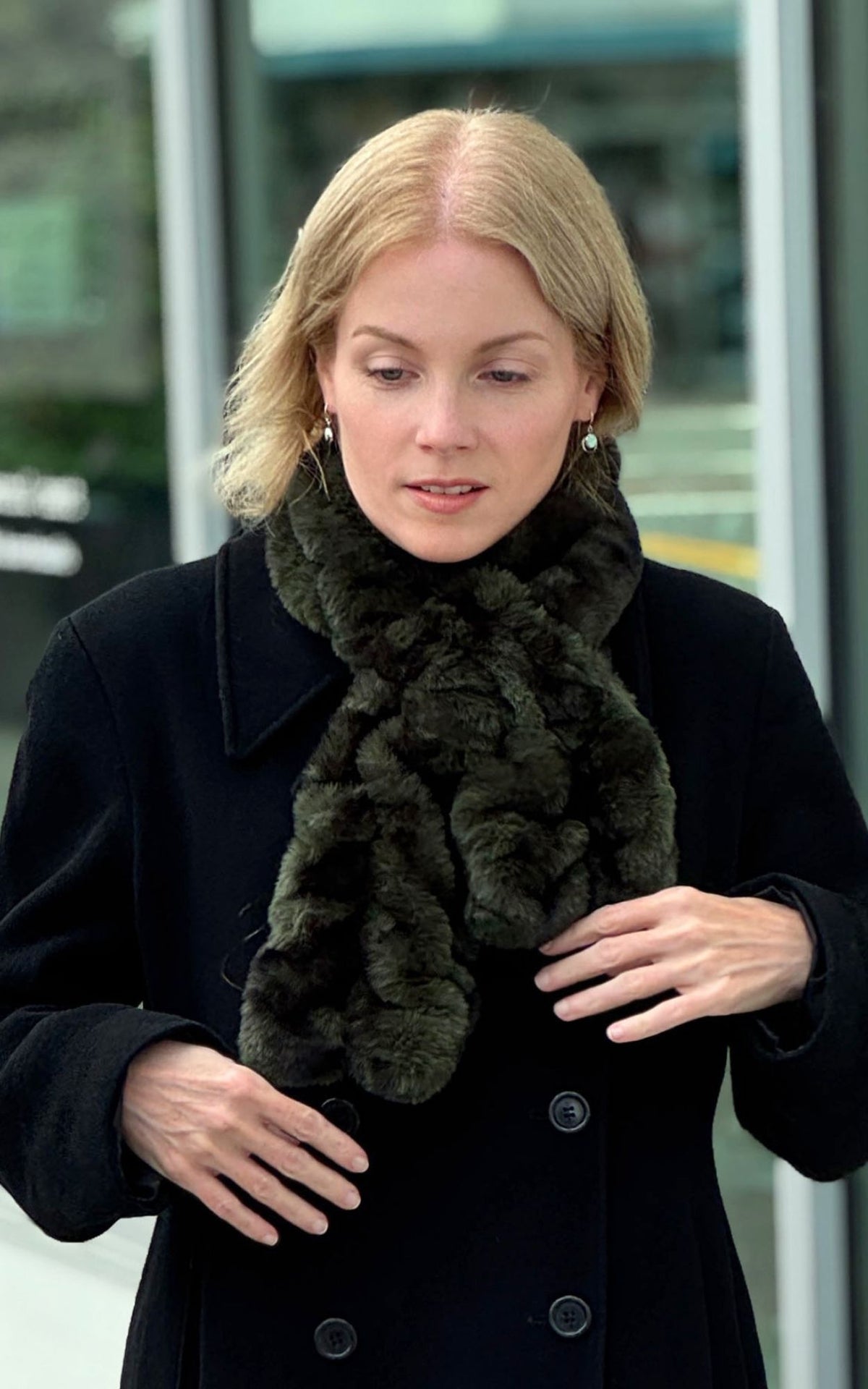 A woman wearing the Royal Opulence Pull-Thru Scarf in Black Pine with a black peacoat while walking down the street. Made in Seattle, WA, USA by Pandemonium Seattle.