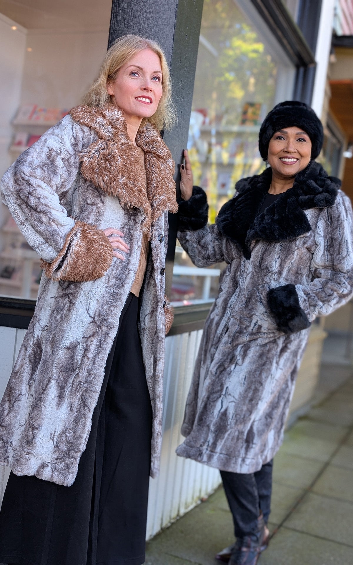 Two smiling woman hanging out by a store front wearing the Roxy coats one in Rock Steady Faux Fur and the Rusty Rock Faux Fur. Handmade by Pandemonium Seattle in Seattle, WA USA
