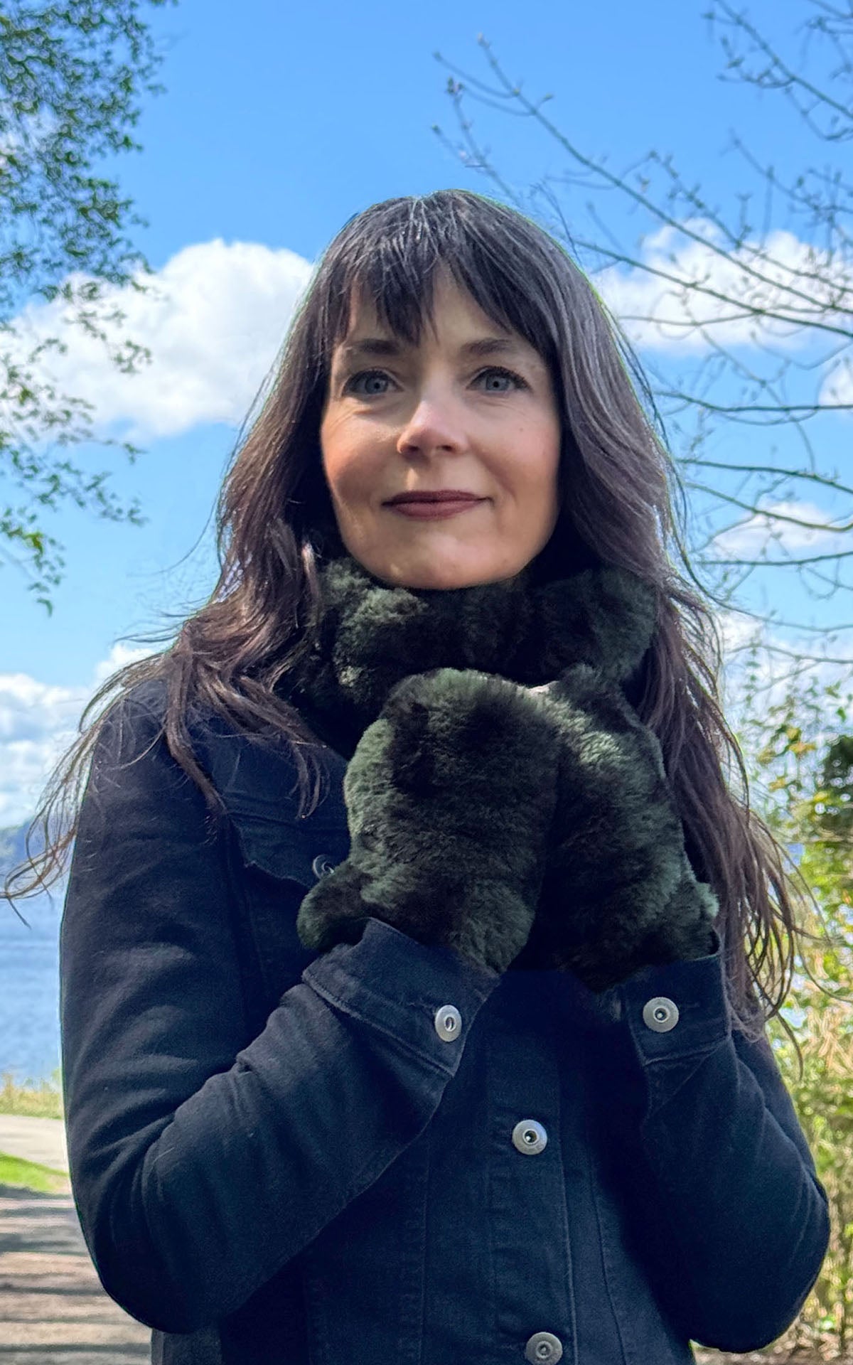 Woman at the beach wearing the Royal Opulence Ear Neck Cozy Wide in Black Pine and Fingerless Gloves Short in Black Pine Faux Fur. Made in Seattle, WA, USA by Pandemonium Seattle.