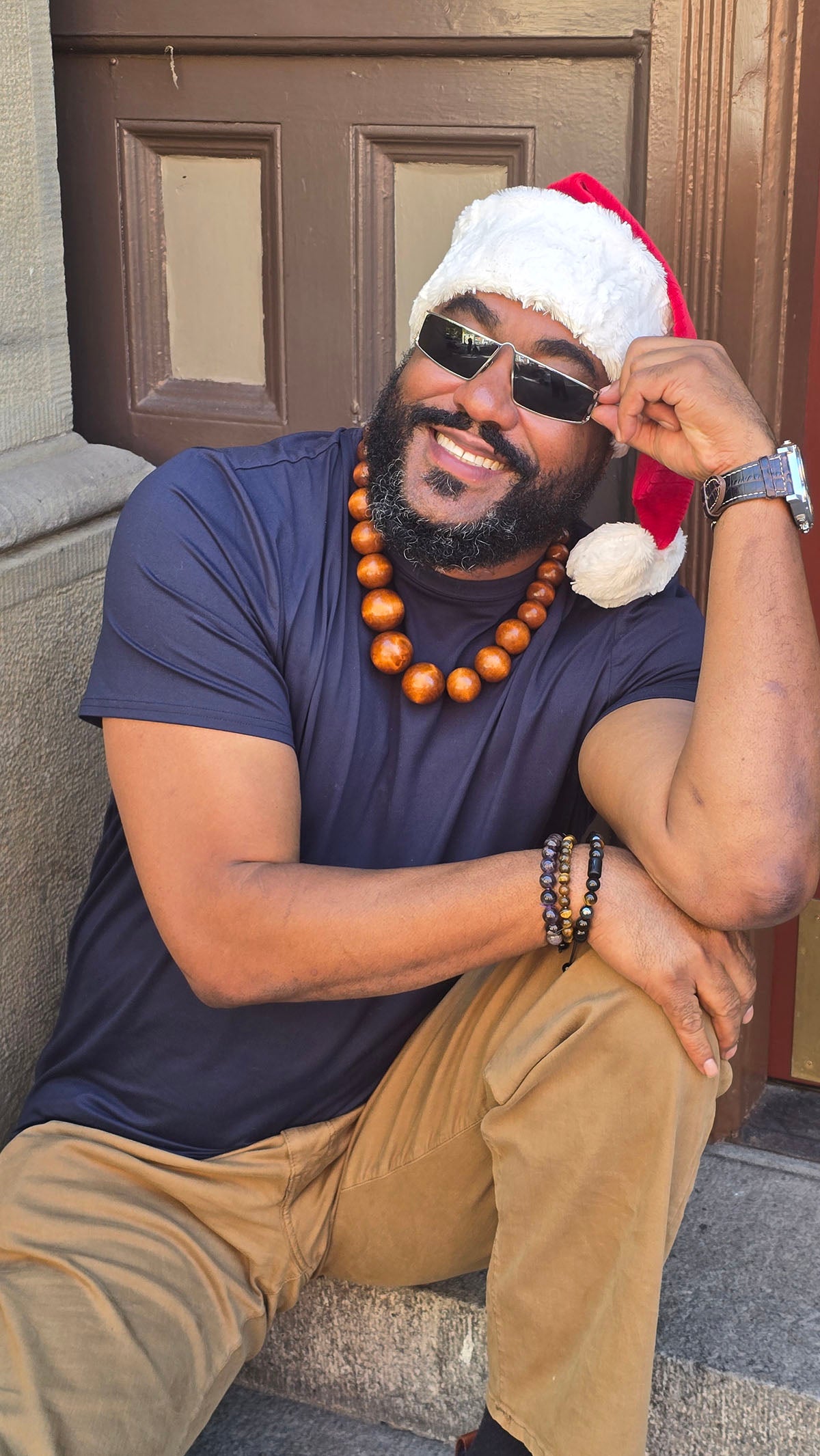 Man wearing the Santa Hat in Red Palm with Cuddly Ivory faux fur cuff and pom. Made in Seattle, WA, USA by Pandemonium Seattle.