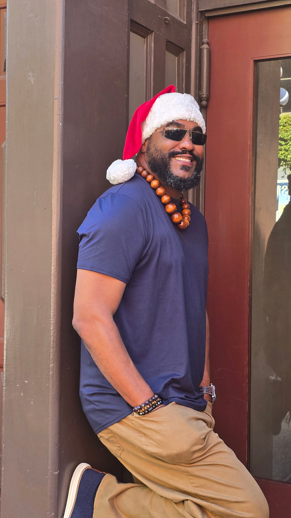 Man wearing the Santa Hat in Red Palm with Cuddly Ivory faux fur cuff and pom, showing the side view. Made in Seattle, WA, USA by Pandemonium Seattle.