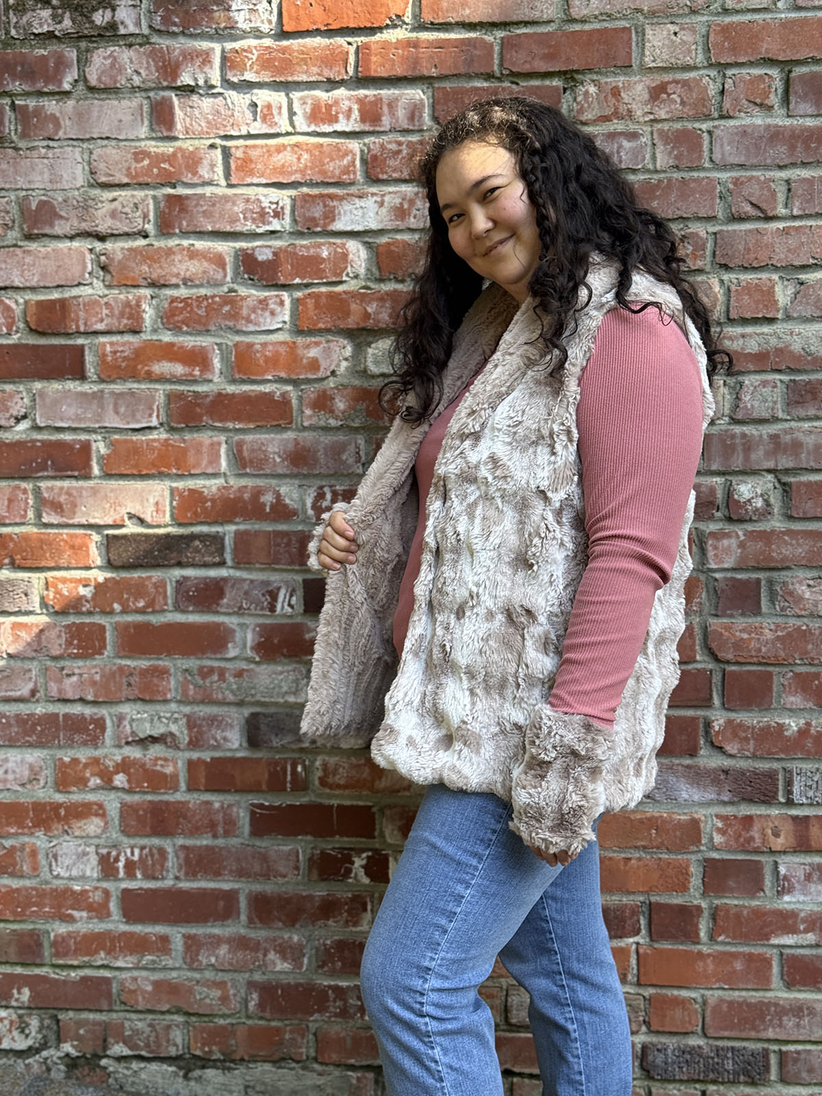 Woman wearing the Shawl Collar Vest in Cloudwalk Honey with reversible Cirrus Honey faux furs. Side view to display the reversible side. Hand sewn in Seattle, Washington by Pandemonium Seattle.