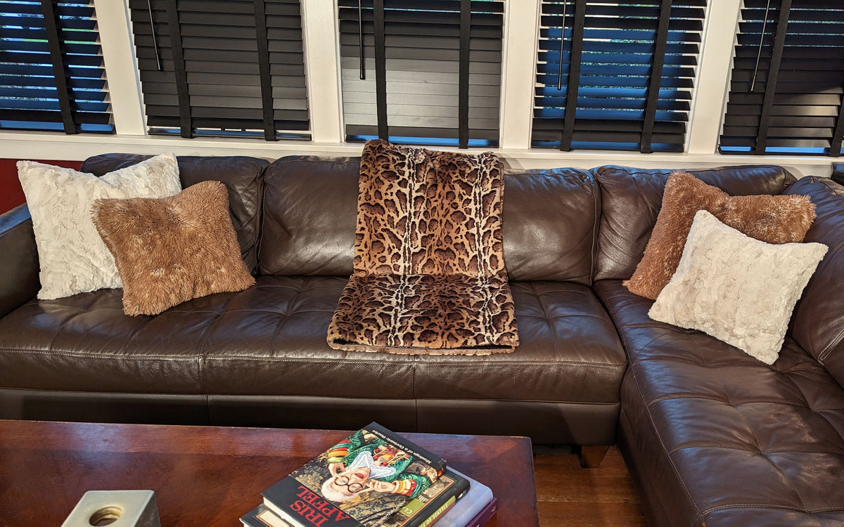Faux Fur Pillow Shams in Sand and Red Fox with animal print Blanket Tissavel Ocelot  on brown leather couch in livinig room | Luxury Faux Fur Throws | Handmade by Pandemonium Millinery