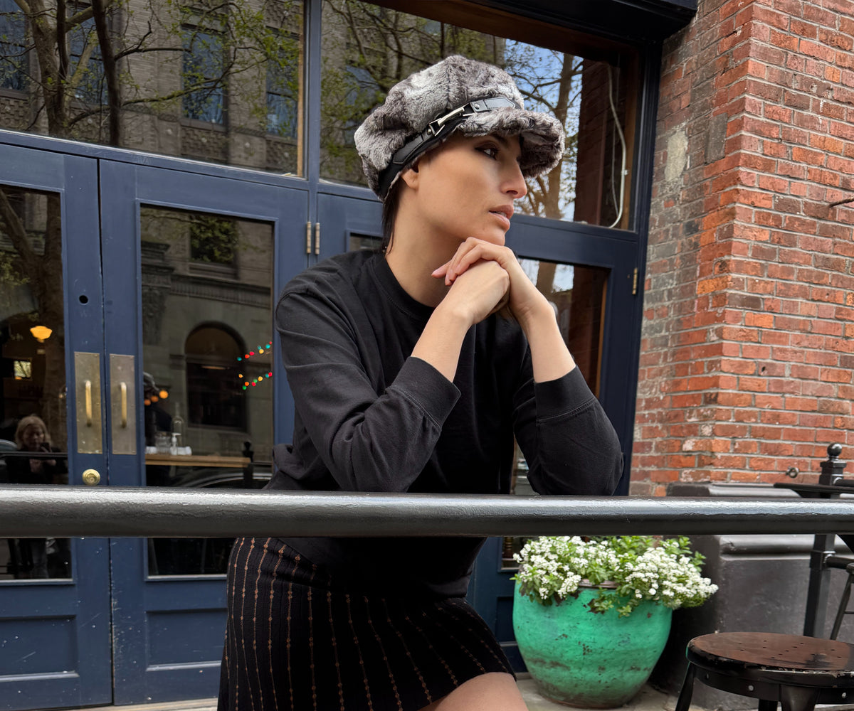 Woman at a downtown Seattle restaurant wearing the Valerie Cap in Rock Steady Faux Fur with a black band and buckle. Made in Seattle, WA, USA by Pandemonium Seattle.
