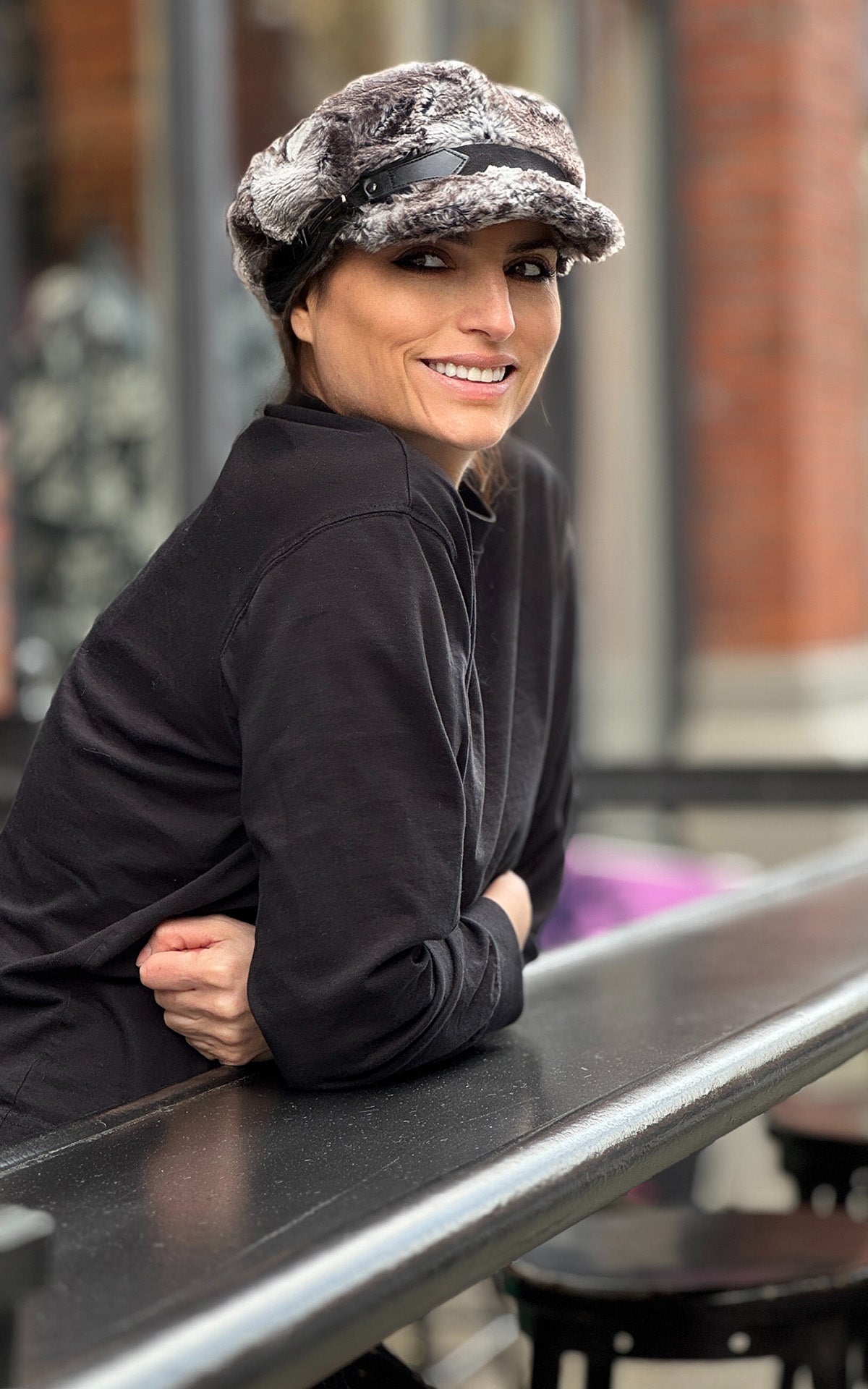 Woman wearing the Valerie Cap in Rock Steady Faux Fur with a black band and buckle. Made in Seattle, WA, USA by Pandemonium Seattle.