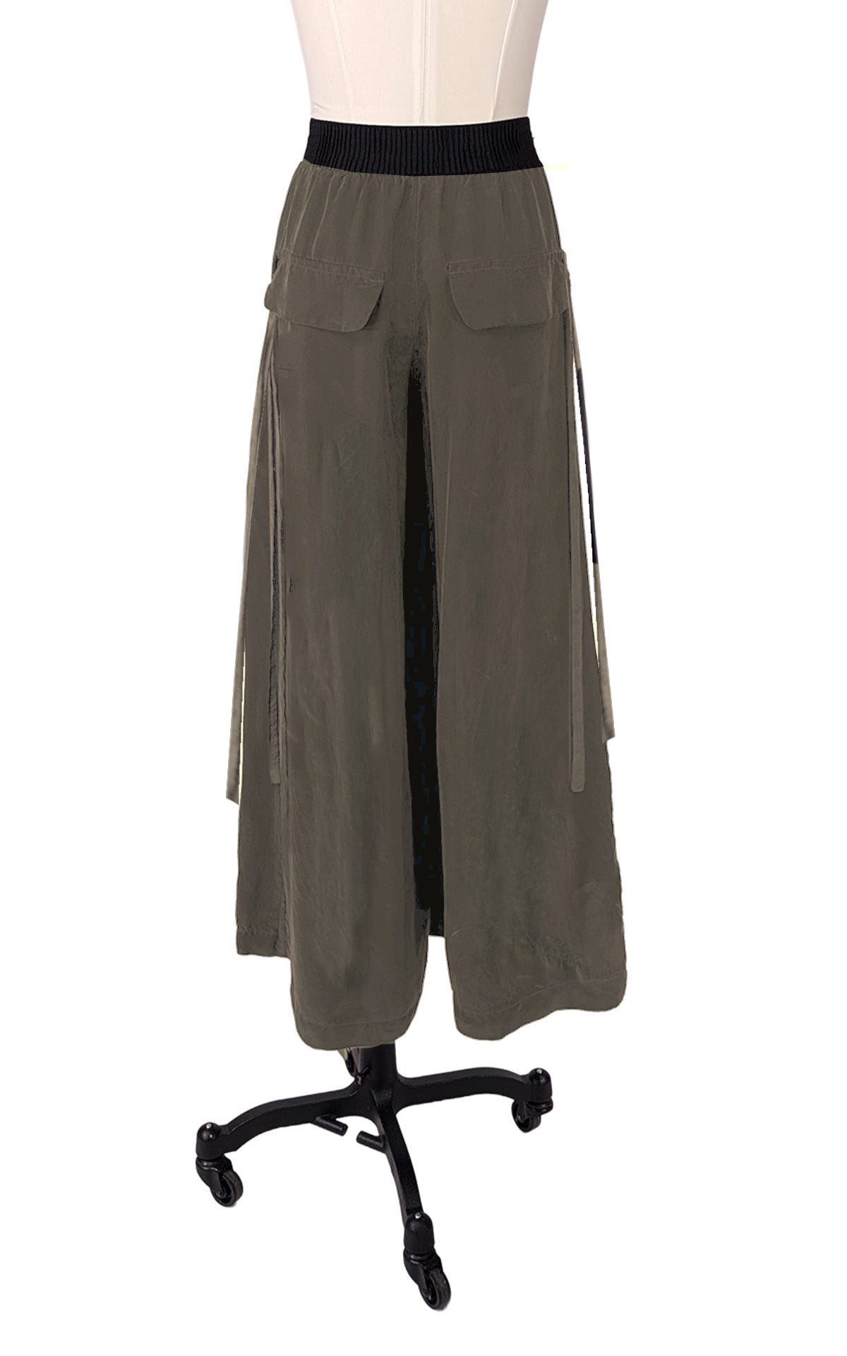 A woman wearing a Cross Over Top in Obsidian with matching Wide Leg Pants, in a park setting. Made in Seattle, WA, USA by Pandemonium Seattle.