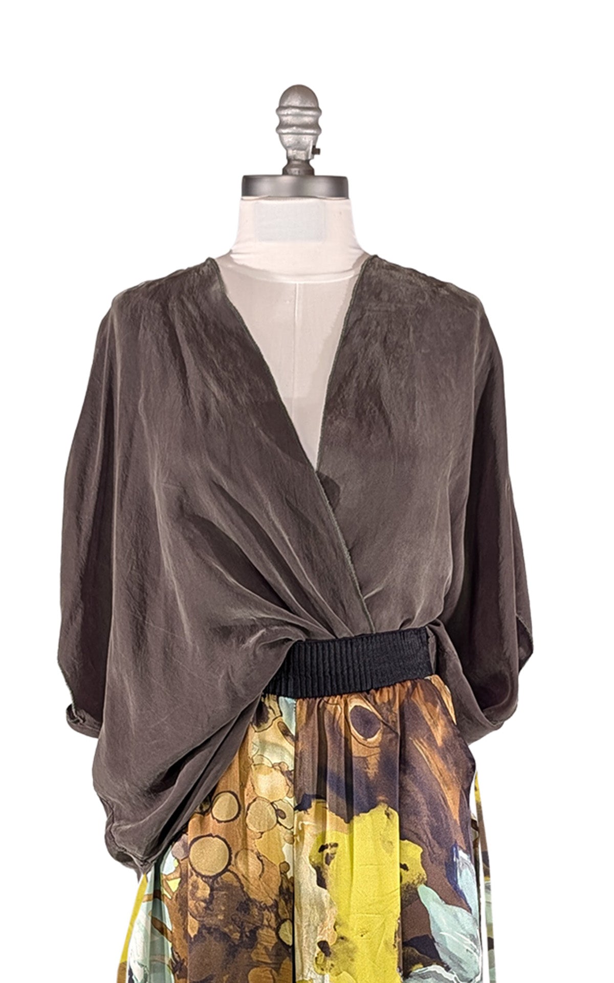A woman wearing the LYC Pandemonium Crossover Top in Dusk Olive Cupro. Shown tucked in to her Wide Leg Pleated Pants in Fiesta Silk Masquerade. Made in Seattle, WA, USA by Pandemonium Seattle.