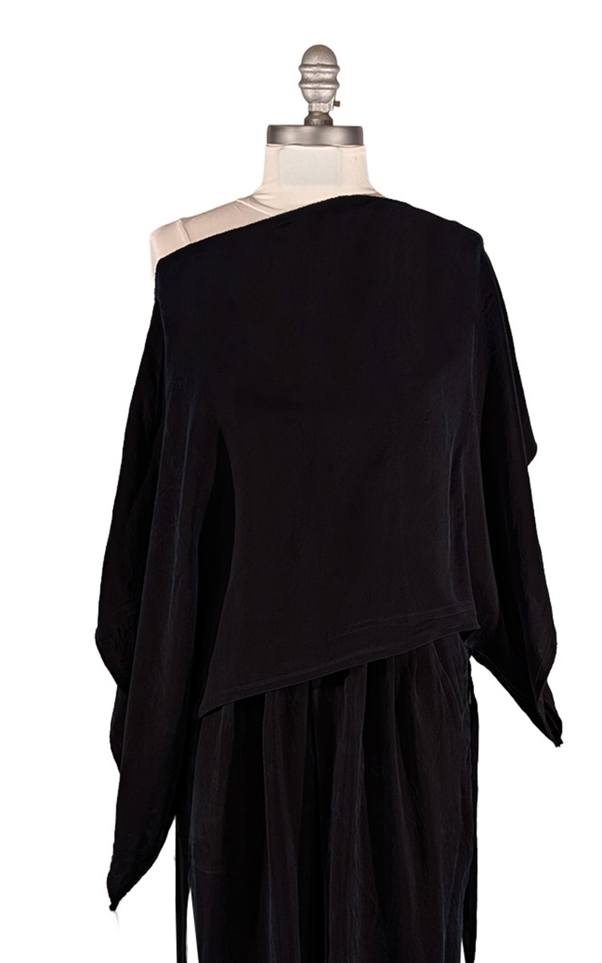 A black draped, asymmetrical Off the Shoulder Top displayed on a mannequin torso against a plain white background. Made in Seattle, WA, USA by Pandemonium Seattle.