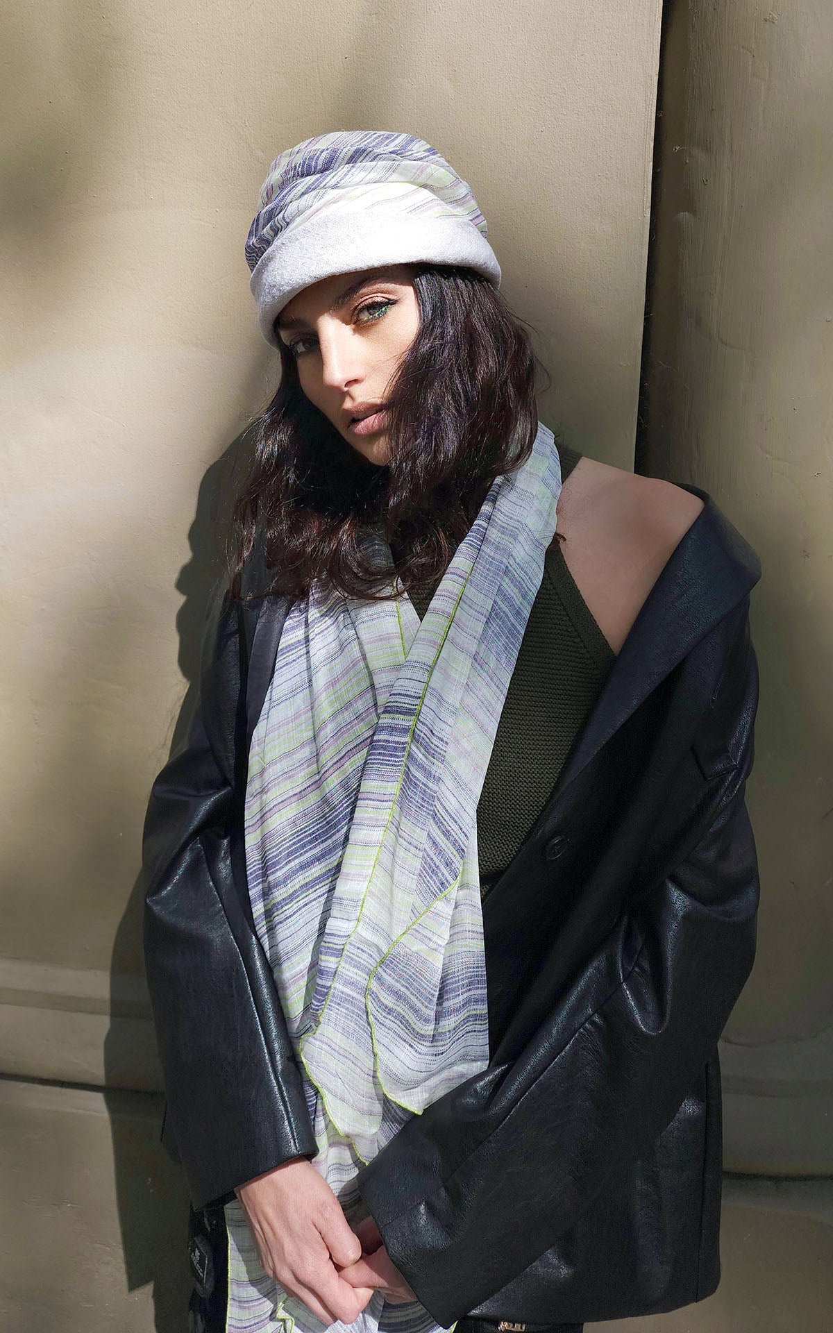 close up of Model leaning against a wall wearing Ana 1930’s Cloche style hat and matching  Ladies Handkerchief Scarf, Large Wrap | Shown in Spring Linen striped print Lime Green, Black, Gray, Ivory | Handmade in Seattle WA | Pandemonium Millinery