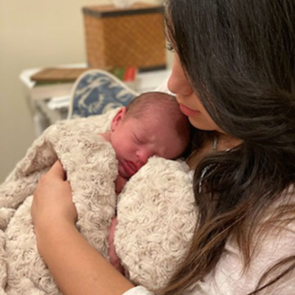 Woman holding a newborn baby wrapped in a Rosebud Brown blanket Handmade in Seattle WA by Pandemonium