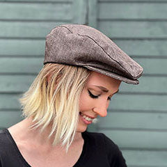 woman in front of green wall wearing light brown driving cap handmade in USA by Pandemonium Seattle