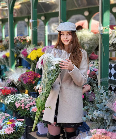 Woman in a Market Place wearing Pandemonium Millinery Charlie Driving Cap | Linen in Metallic Silver | Handmade in Seattle WA