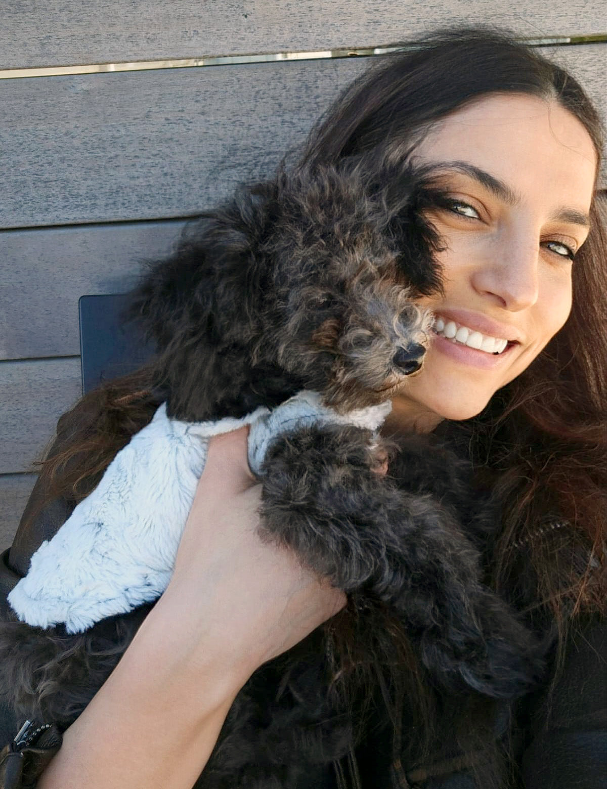 Model holding a dog wearing reversible Dog Coat Side View | Winter Frost off white Faux Fur reversing to Black | Handmade in Seattle, WA USA