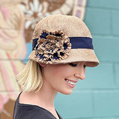model wearing champagne tumbleweed cloche hat with large navy flower handmade in the usa by pandemonium millinery