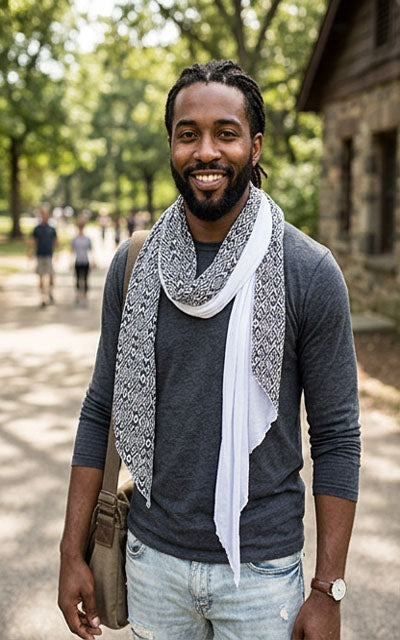 Man wearing a gray sweater and Pandemonium scarf in casbah and milky way outdoors with trees and people in the background