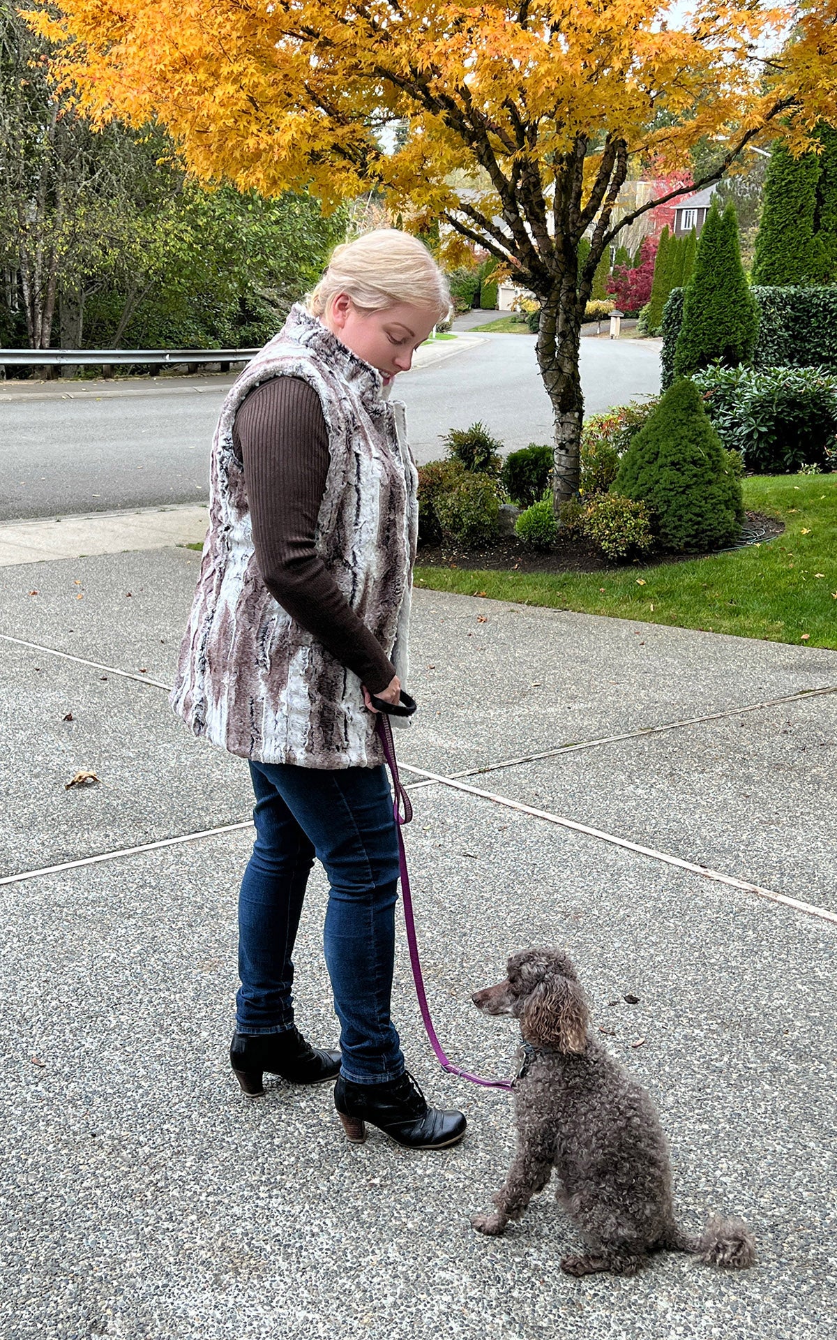 Woman sitting on steps with dog wearing the Short Mandarin Vest in Birch Faux Fur with reversible Cuddly Ivory Faux Fur. Custom made by Pandemonium Seattle.