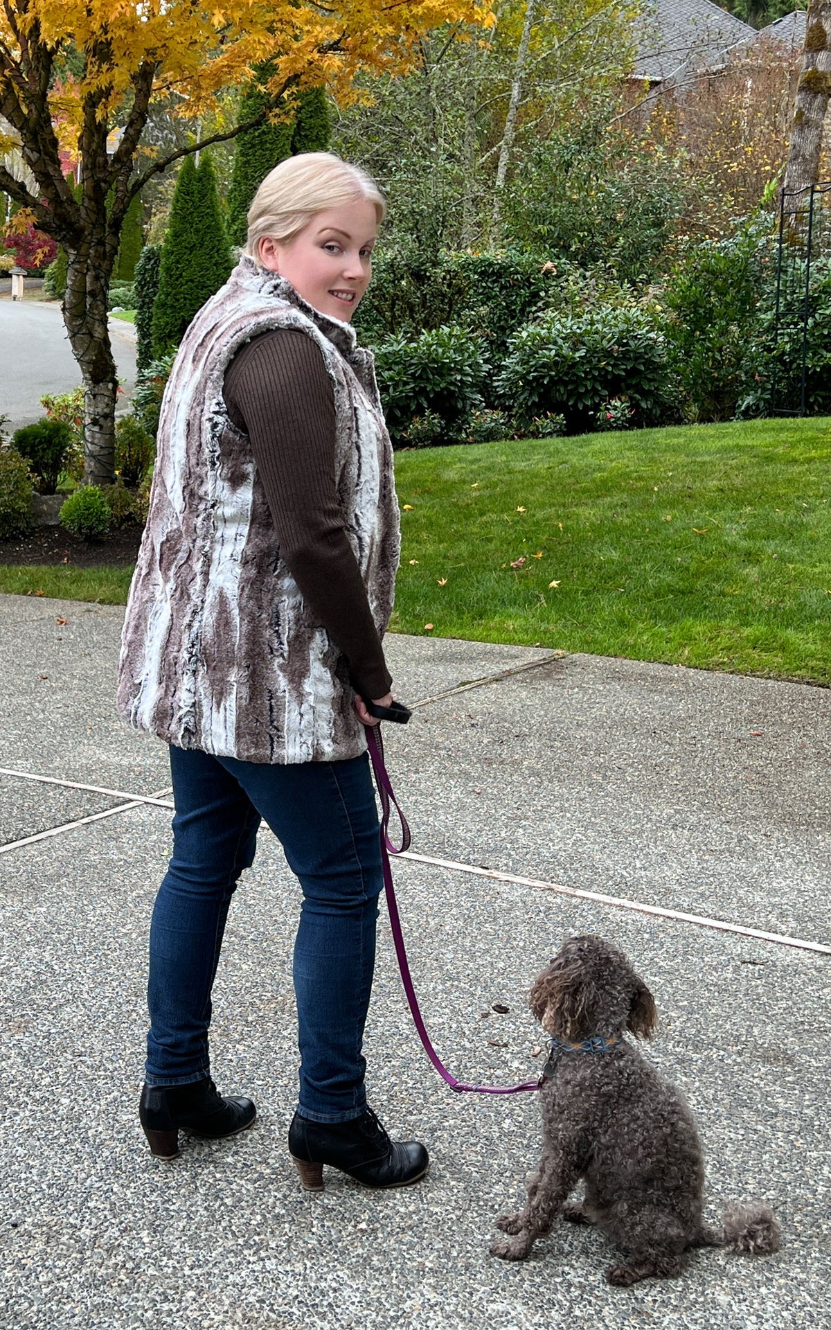 Woman walking dog wearing the Short Mandarin Vest in Birch Faux Fur with reversible Cuddly Ivory Faux Fur. Custom made by Pandemonium Seattle.