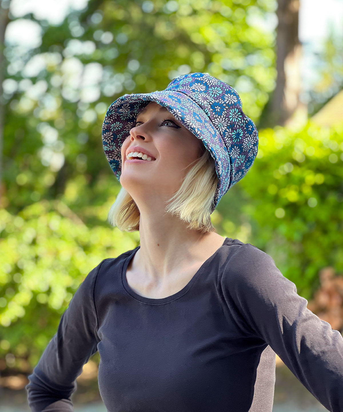 woman looking up while wearing a Molly Bucket Style Hat in Blue and Purple Floral Blossom Cotton | Handmade By Pandemonium Millinery in Seattle WA