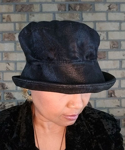 Woman wearing Molly Bucket Style Hat Vegan Leather in Outback Black with Velvet leaves and Floral Button Brooch | Pandemonium Millinery | Seattle WA