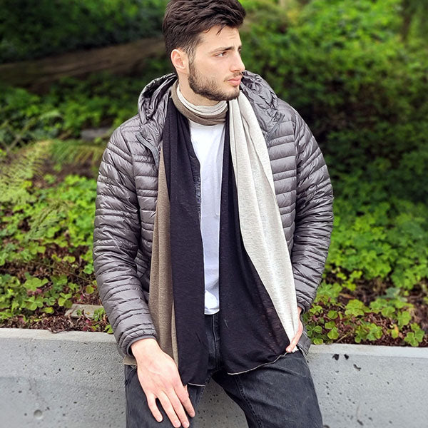 A man's lightweight scarf featuring a modern color-blocked design in complementary tones, draped over a casual outfit for a stylish seasonal layer.