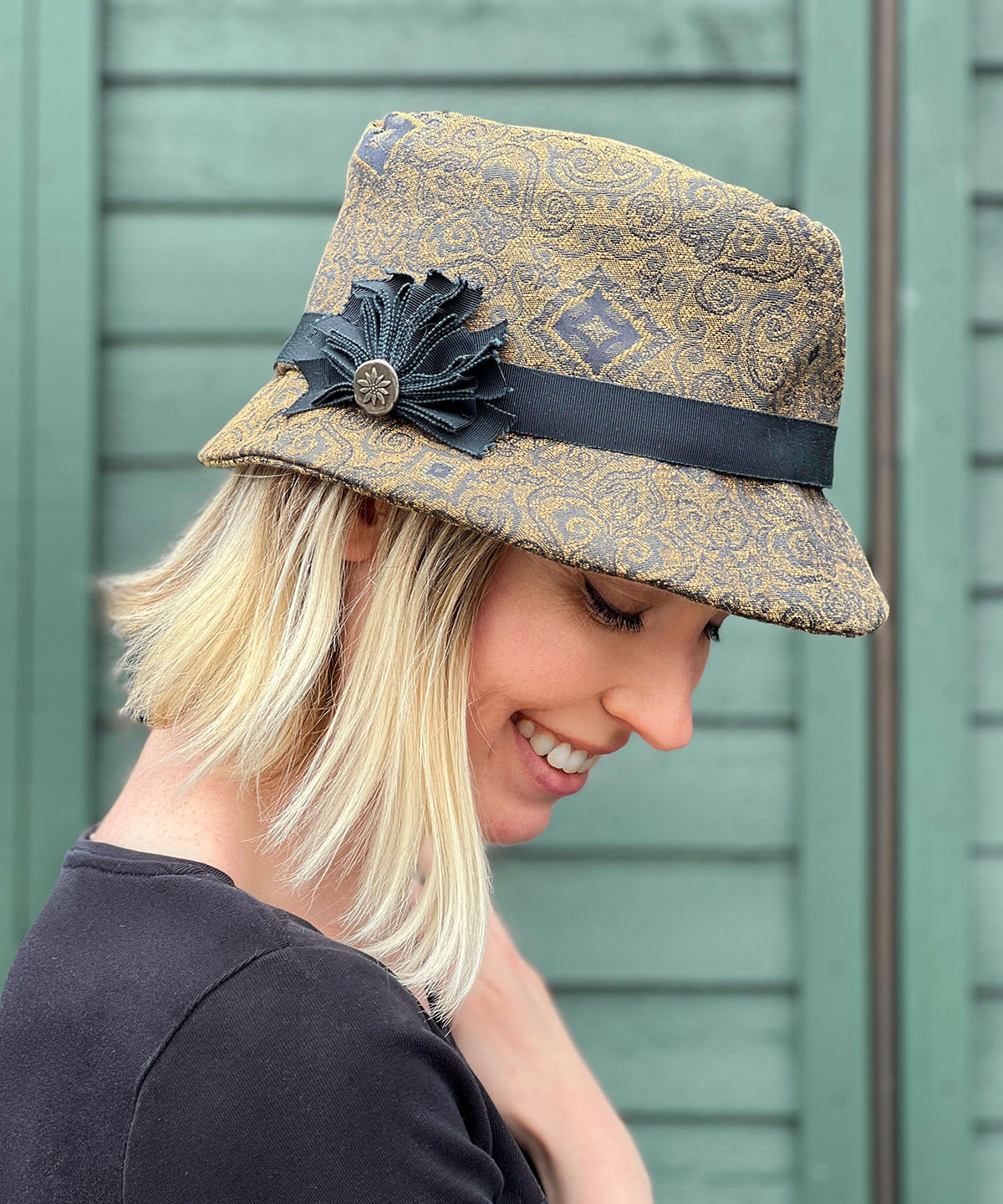 Woman smiling while wearing Olivia Fedora Hat in Rubino Upholstery with Custom Grosgrain Brooch | Handmade in Seattle WA | Pandemonium Millinery