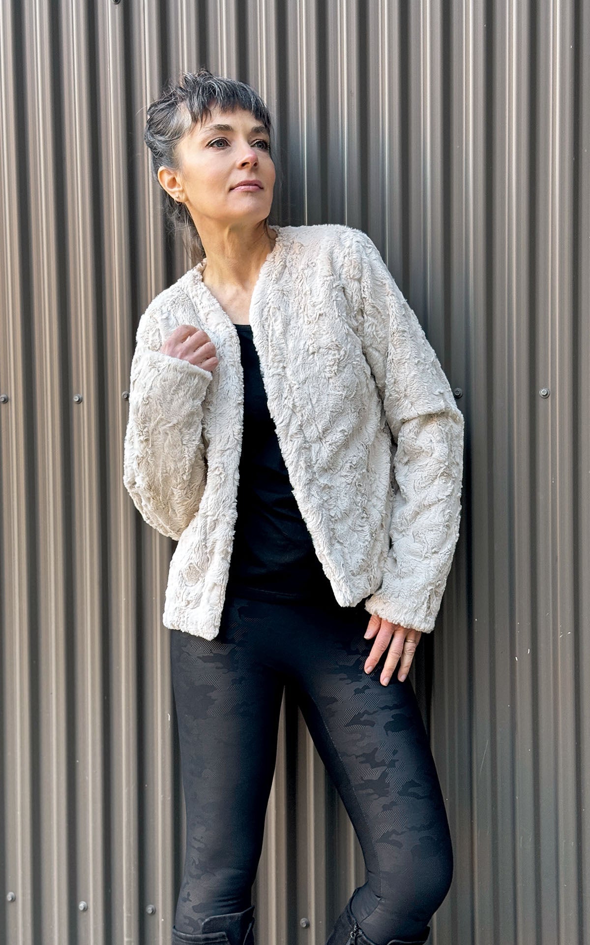 Model leaning against brown wall  in the Onassis Coat Cuddly Sand Fur Fur |  Handmade By Pandemonium Seattle  | Seattle WA USA