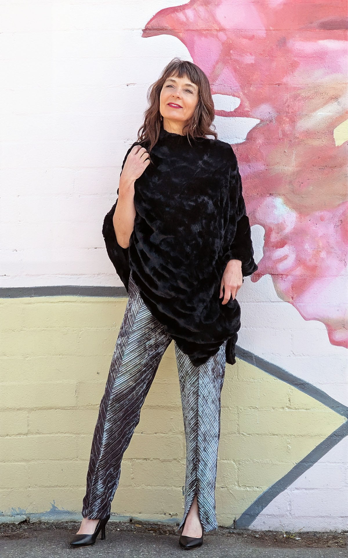 Model standing against a mural wearing a Poncho | Royal Opulence Faux Fur in Onyx | Pandemonium Millinery | Seattle, WA USA