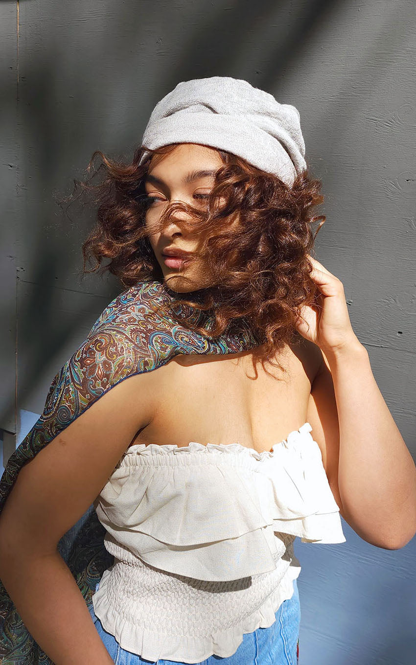 Model against a Gray wall wearing  Rowdie Slouchy style hat and  Handkerchief Scarf, Wrap |Peacock Paisley Chiffon in blue, greens, and browns | Handmade in Seattle WA | Pandemonium Millinery