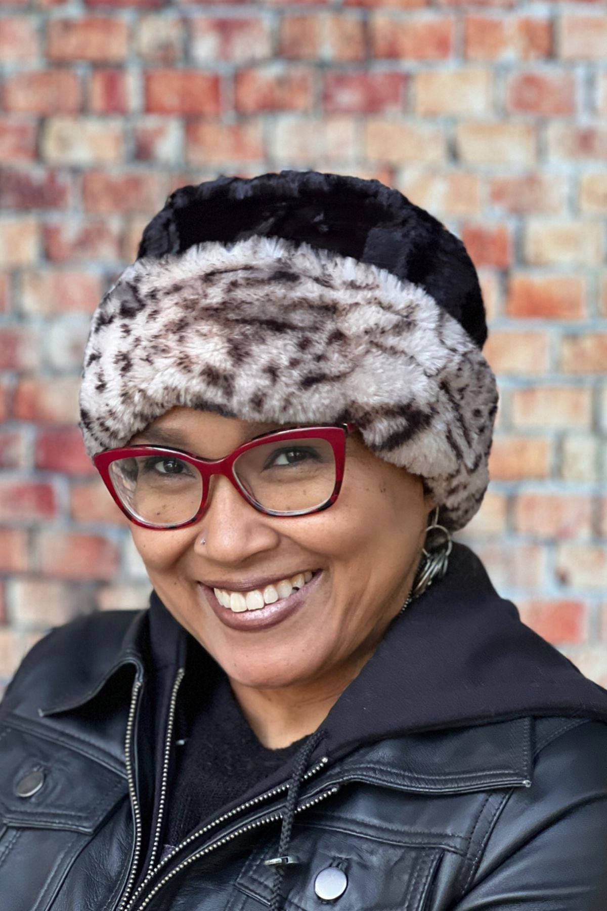 Woman wearing a Royal Opulence Cuffed Pillbox in Snow Leopard with Cuddly Black. Handmade by Pandemonium Seattle.