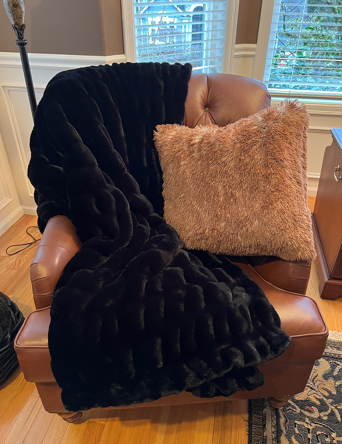 Royal Opulence Faux Fur Throw in Onyx with a Red Fox Pillow, draped over a leather chair. Handmade by Pandemonium Seattle.